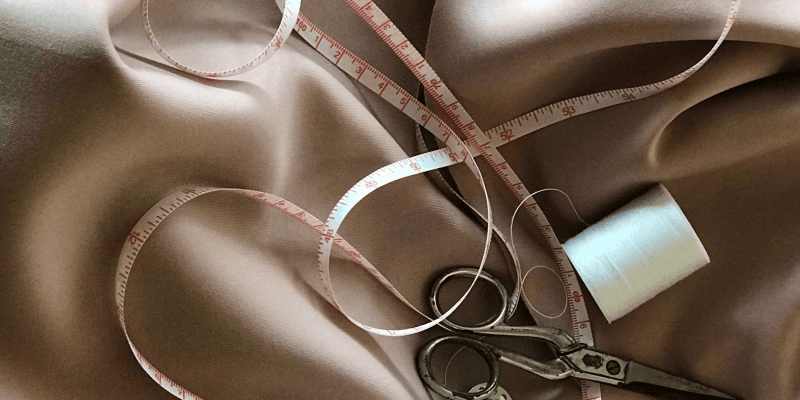 Measuring tape and tailoring tools on satin fabric